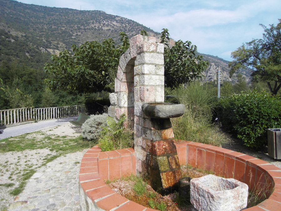 Steinerner Brunnen in einem bepflanzten Garten